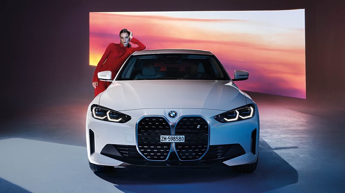 Frau lehnt an weissem BMW i4 im Studio